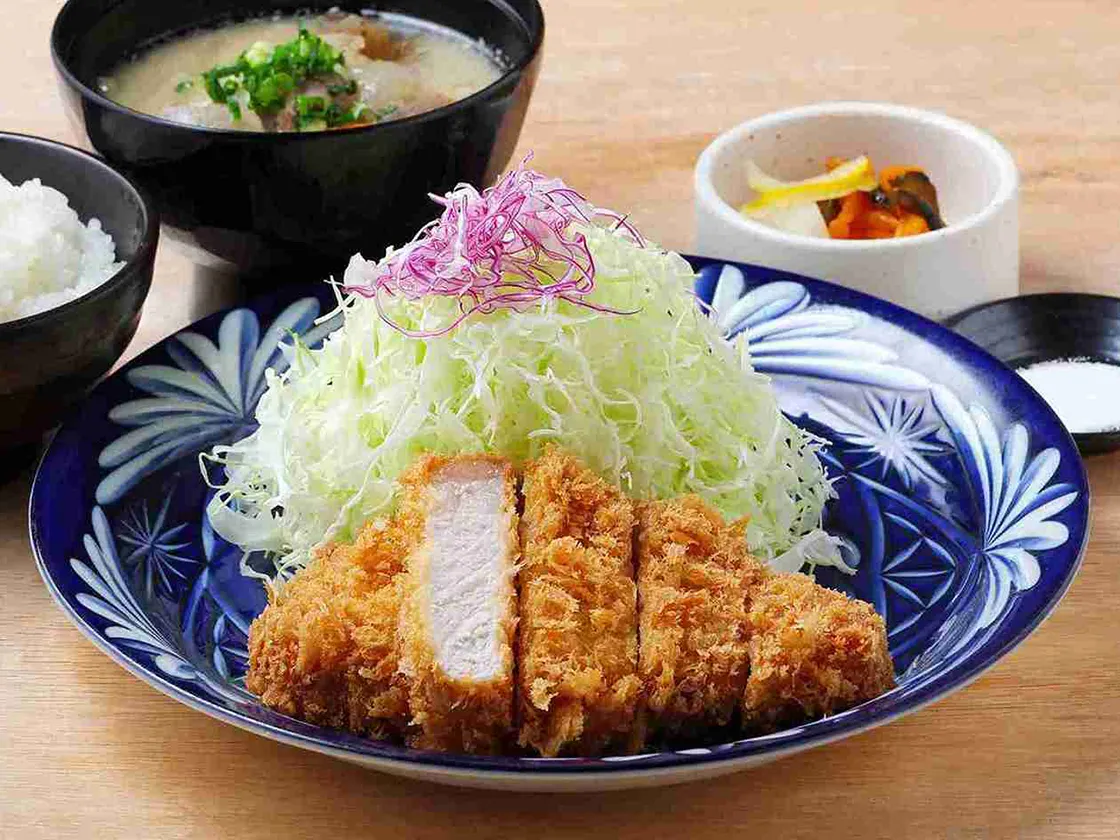 お皿に盛り付けられたとんかつとキャベツ、ご飯、味噌汁、漬物